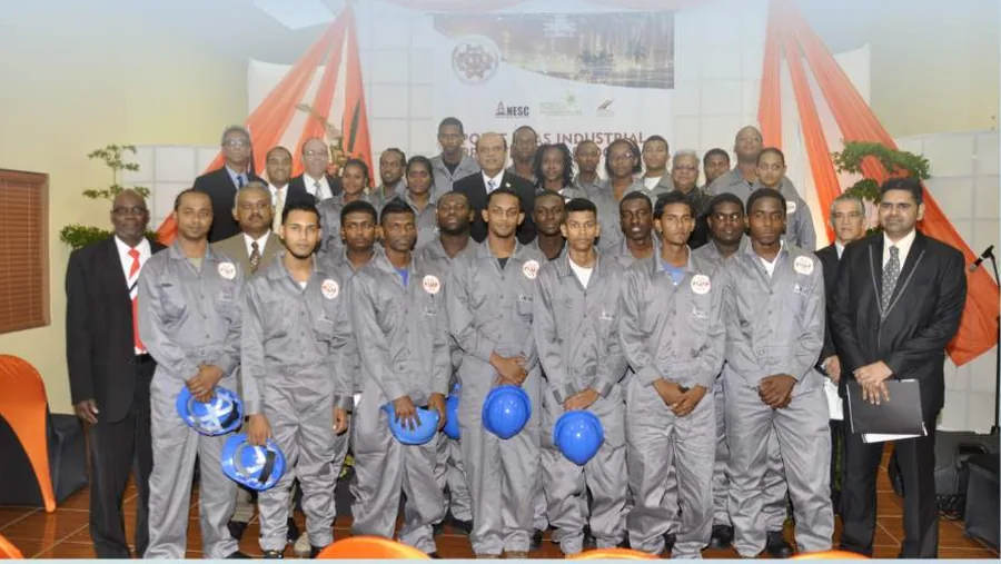 KAMIL trainees in coveralls and hard hats at a certification ceremony, with agency staff in suits